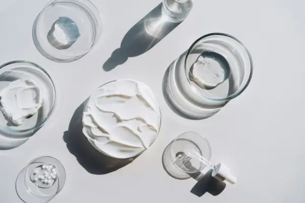 Many glass pipettes spilling drops of different moisturizing lotions on luxury silver background. Polyglutamic acid is new hyaluronic acid. Macro photography