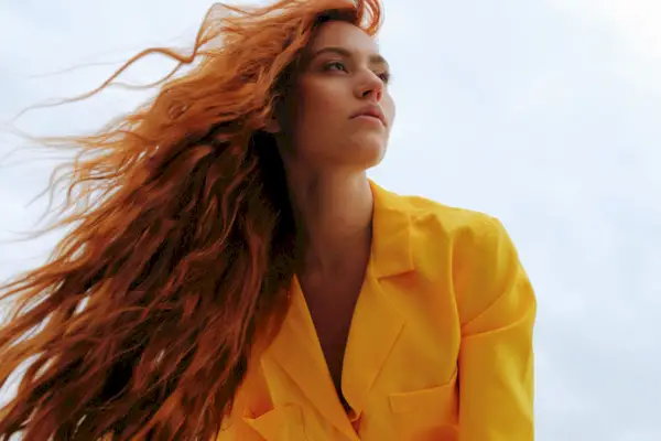 Portrait of a young woman in yellow clothes against the sky