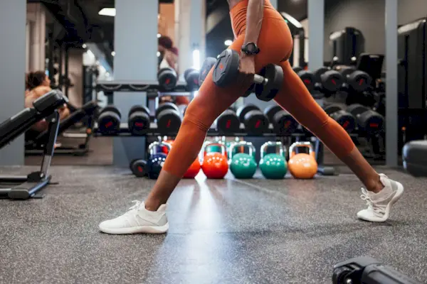 Anonymous Sportswoman Using Dumbbells for her Workout Session at the Gym