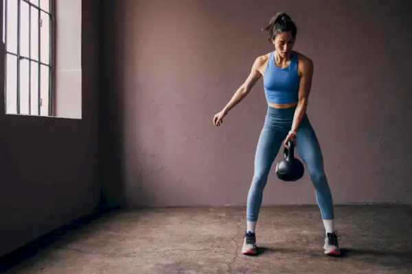 Young woman exercising with kettlebell on sunny day