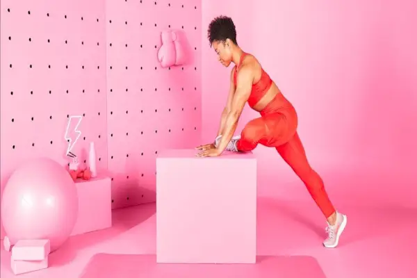 woman stretching her glutes in a pink room
