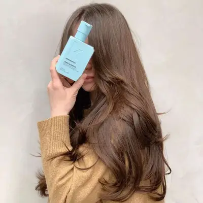 A woman holds a bottle of Kevin.Murphy product