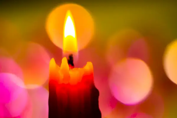 Bright Lighted Candle with Colourful Background.