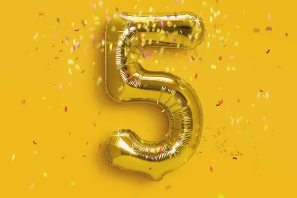 number 5 foil golden ballon in gold background with confetti