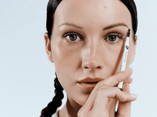 Model holding the Glossier Boy Brow Arch Pencil