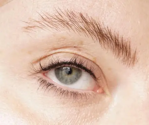 photo of green eye after lash enhancement tattoo with visibly darker lashline