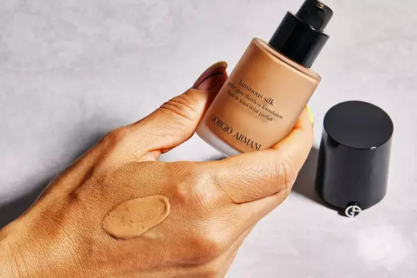 A hand holding an open bottle of Giorgio Armani Beauty Luminous Silk Foundation