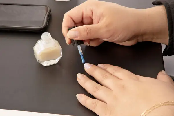 Person painting their nails with Taupe Coat Nail Polish in Pearlie