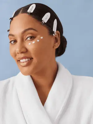 Ayesha Curry smiling with dots of eye cream on her face