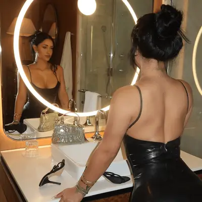 Leah Kateb looking into a bathroom vanity mirror.