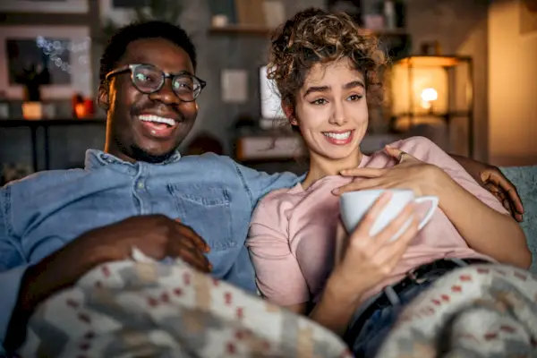 Multiracial loving couple watching tv in the evening