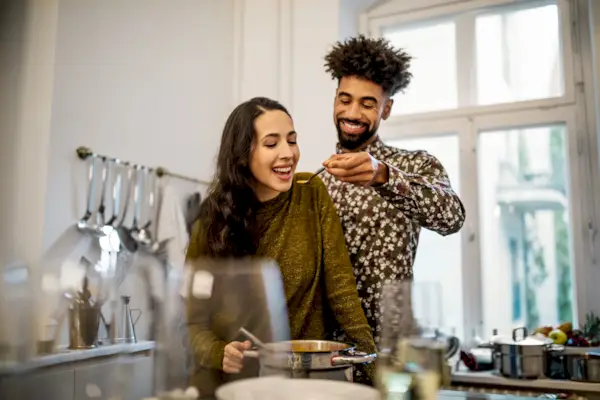 Man feeding pumpkin soup to girlfriend in kitchen