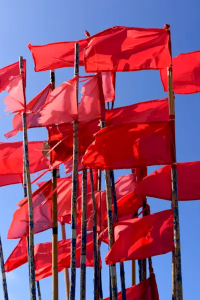 Red fishing buoy flags on the boat moored in the dock against the blue sky