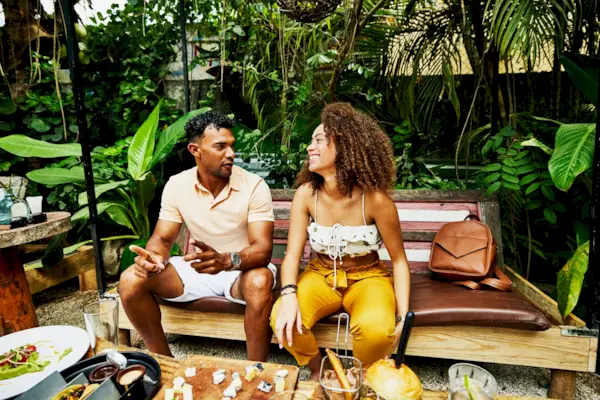 Medium wide shot of laughing woman sharing lunch with boyfriend at outdoor cafe