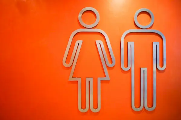 Close-Up Of Metallic Restroom Sign On Orange Wall