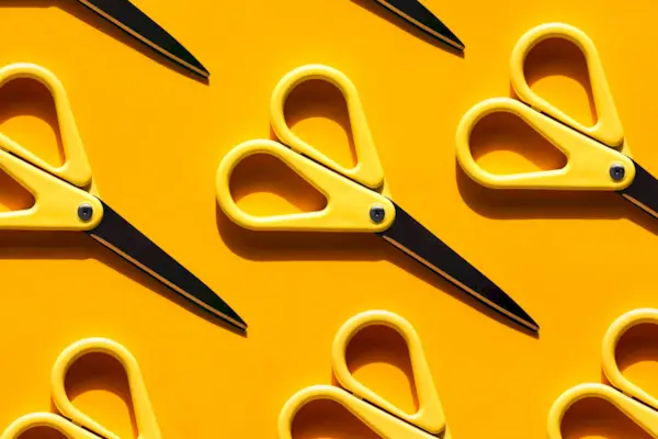 Yellow scissors with shadow on illuminating yellow background. Back to school concept. Trendy colors of the year
