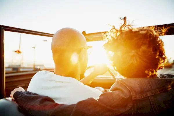 Couple driving convertible at sunset