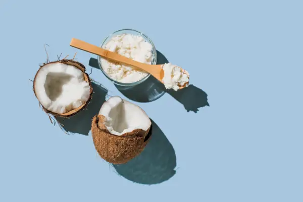 Ripe coconuts, coconut oil on blue background. Health and wellness concept. Minimal flat lay style. Top view, copy space.