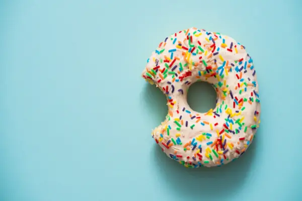 One bite missing of donut on blue background