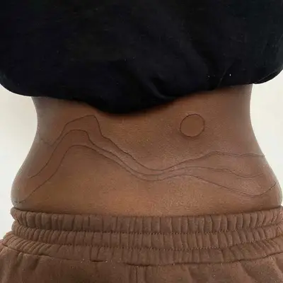 Custom abstract stick-and-poke tattoo on lower back