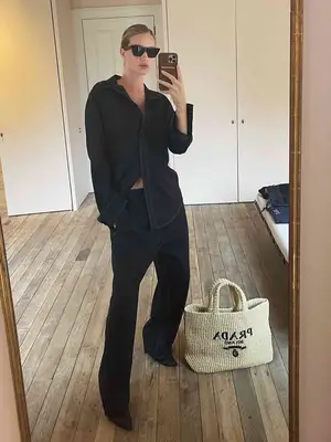 Rosie Huntington Whiteley wearing all black outfit with Prada raffia tote on floor