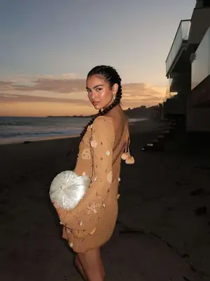 Woman wearing mesh dress and carrying pearl shell clutch