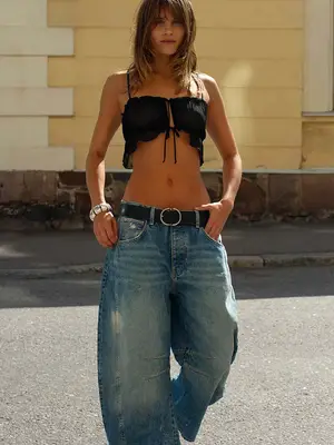 model wearing black tie crop top with blue barrel jeans and black belt with silver buckle