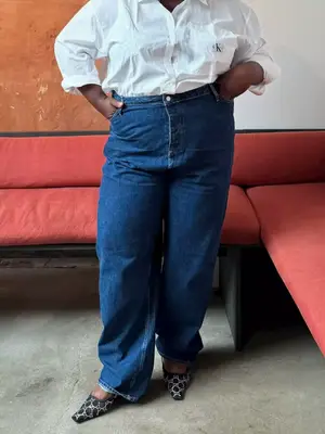 Abisola Omole wears a white button-down shirt, jeans, and black and white shoes