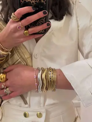 Woman wearing gold and silver stacked bangles and gold and pink gem rings