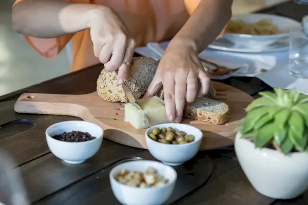 Woman cutting cheese and bread on chopping board