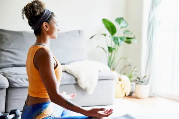 Woman in lotus position while working out in living room of home
