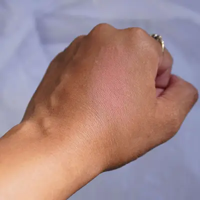 Close-up of hand with swatch of peachy pink blush