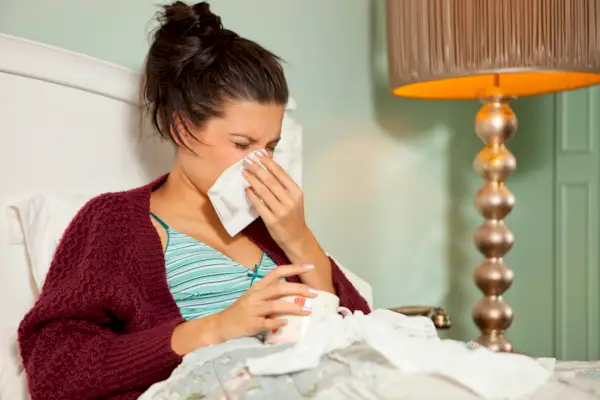 młoda kobieta w łóżku z przeziębieniem