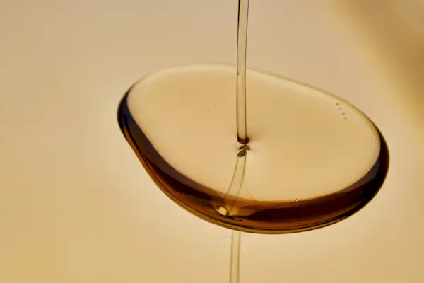 Texture of pouring cosmetic oil on a golden background.