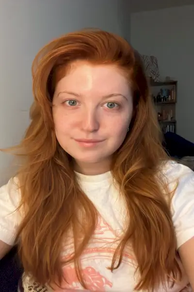 osoba s dlouhými vlnitými oranžovými vlasy na sobě bílé tričko