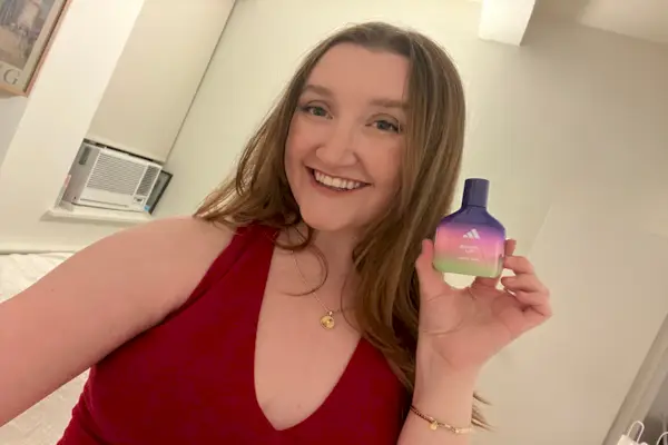 pessoa segurando um frasco de fragrância adidas em um ambiente interno bem iluminado