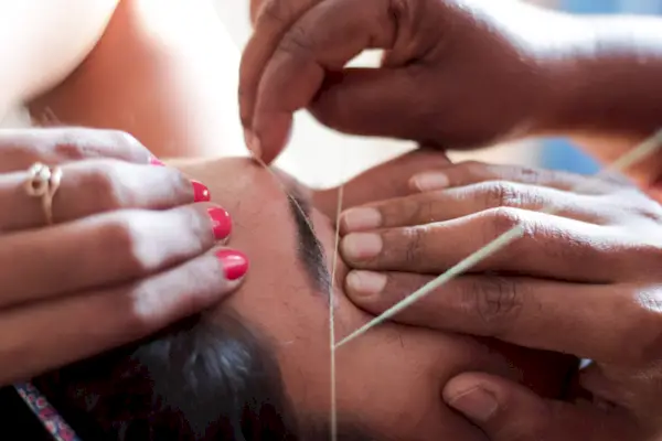 Cropped Hands Of Beautician Threading Woman Eyebrows