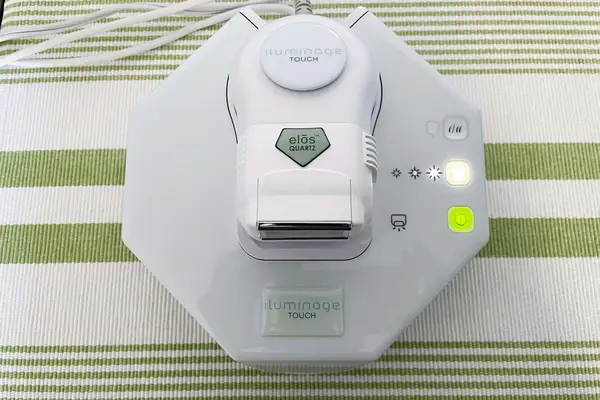 Iluminage Touch 4ever Home Permanent Hair Removal IPL & Radio Frequency System displayed on green striped cloth