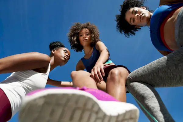 Young female athletes in sportswear against blue sky