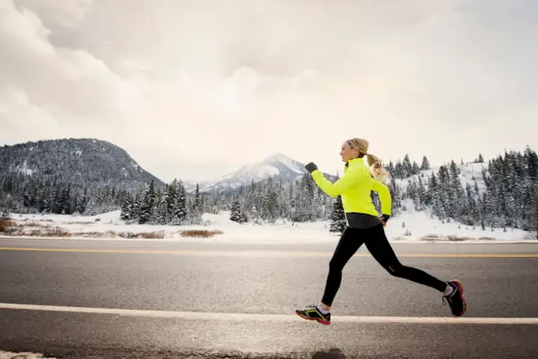 Caucasian woman running on snowy road
