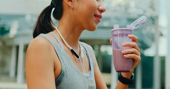 Protein isolate powder. Unflavored whey protein in measuring scoop and drinking glass in bright sunlight