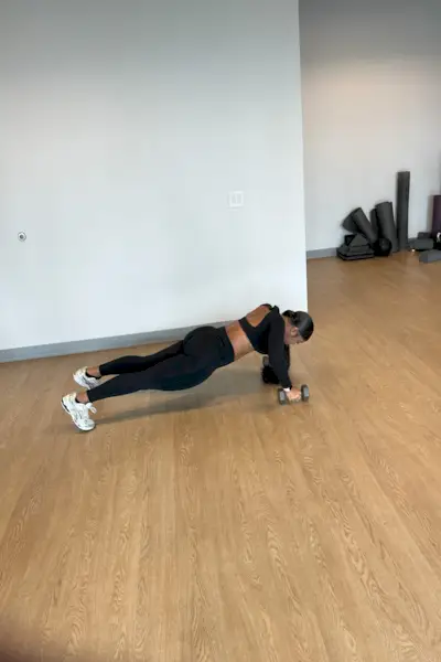 Persona que realiza un entrenamiento con una mancuerna en un gimnasio.