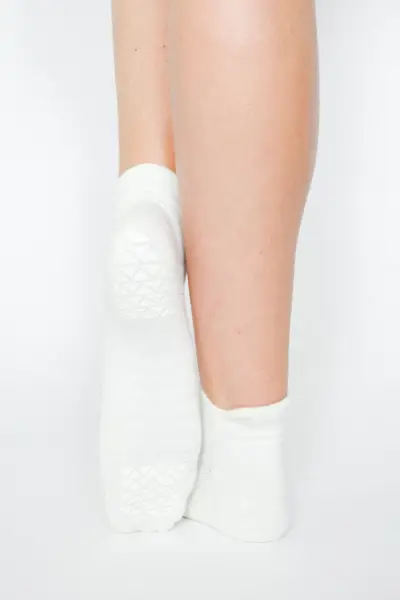 Back view of young woman doing yoga against a gray wall. Copy space