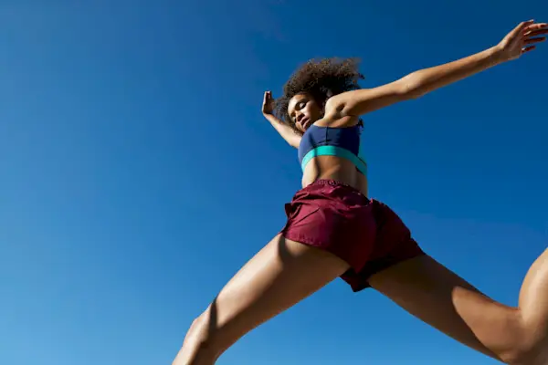 Young woman exercising against clear sky