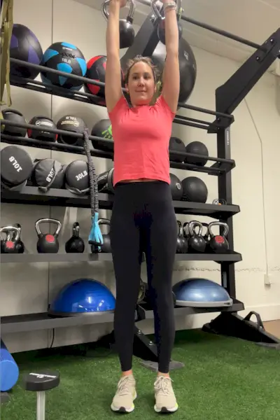 pessoa realizando um exercício aéreo com kettlebells em uma academia