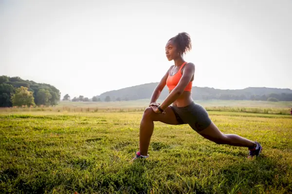Young female runner stretching in rural park