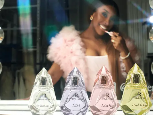 Jackie Aina posing near Forvr Mood fragrances