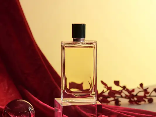 Perfume bottle in warm-toned environment with red curtain and flowers