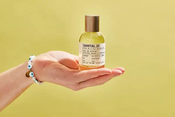 A person holds up a bottle of Le Labo Santal 33 Eau de Parfum