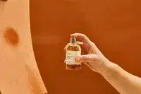 A person sprays Le Labo Santal 33 Eau de Parfum onto paper